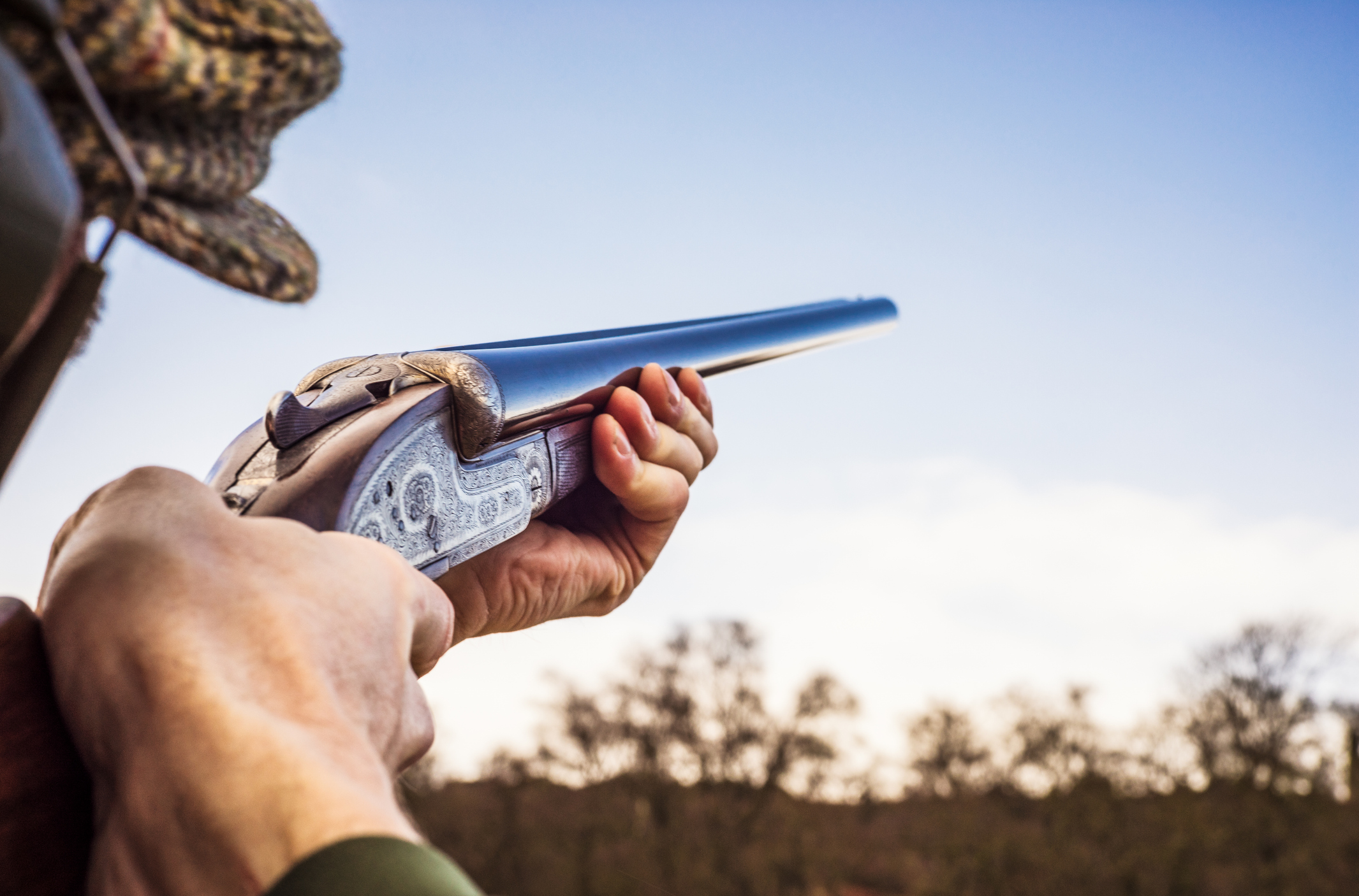 Hunter holding a shotgun up, aiming to fire.